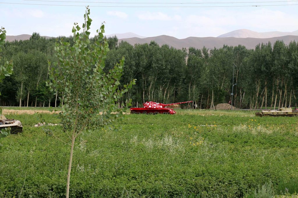 Red polka-dot Soviet military tank in a green field in Bamian