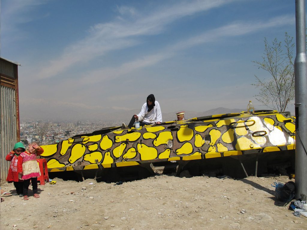 Yellow pear-patterned Soviet military vehicle on a hilltop overlooking Kabul