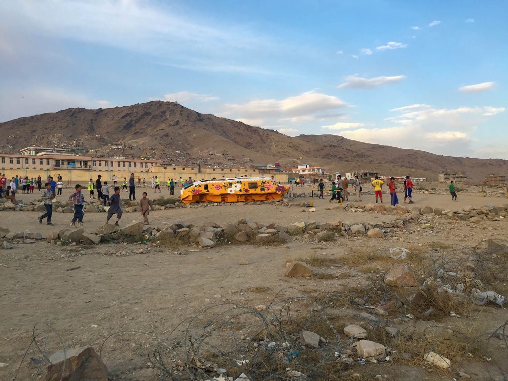 Orange-painted Soviet military vehicle with children in Khair Khana, Kabul